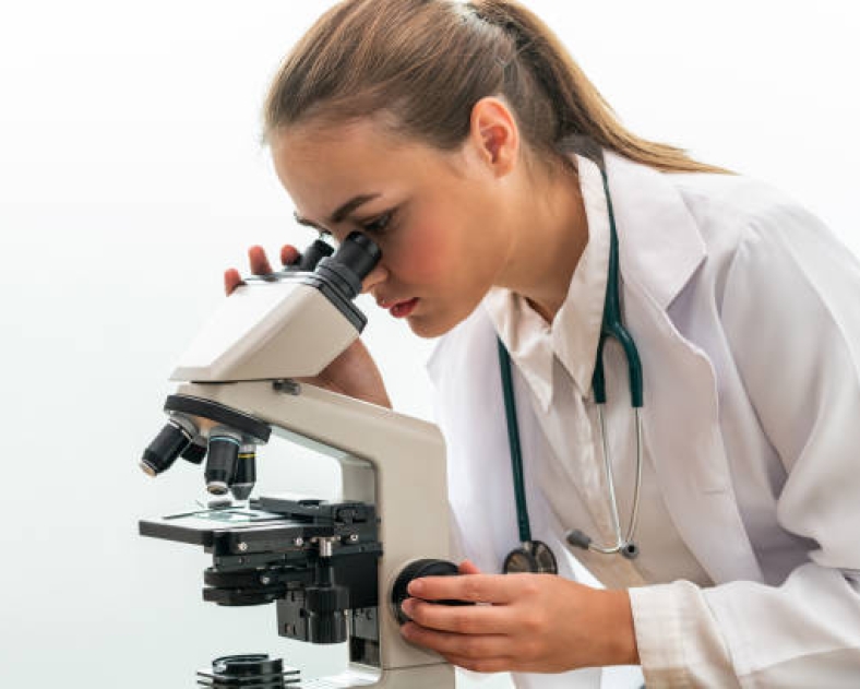 Young female doctor working using microscope in hospital laboratory. Medical and medicine technology research and development concept.
